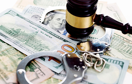 Gavel and Handcuffs on Top of Dollar Bills To Represent the Penalties of Money Laundering