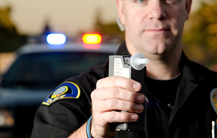 Close-Up of Police Officer Holding a Breathalyzer in His Hand