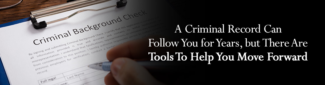 Close-Up of a Person's Hand Holding a Pen in front of a Criminal Background Form