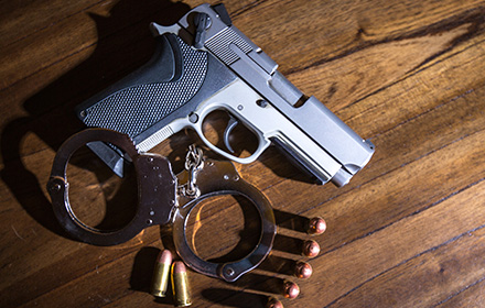 Firearm and Bullets Next To Handcuffs To Represent the Legal Penalties of Firearm Crimes