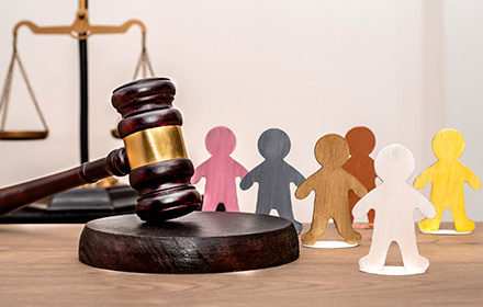 Child Figurines Around Gavel and Scales of Justice To Represent the Prosecution of Child Pornography Crimes
