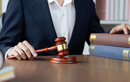 Lawyer Holding Gavel with One Hand and Books With the Other During Criminal Investigation